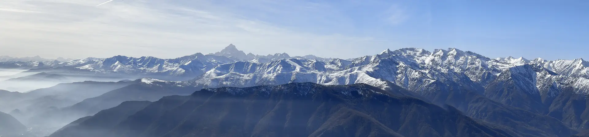 Snow-covered Alpine skyline seen from above the haze